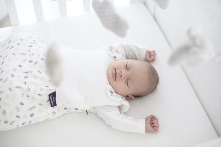 Träumeland: Baby schläft glücklich im Babybett.